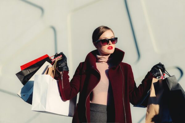 Kobieta w eleganckim płaszczu z torbami na zakupach Black Friday